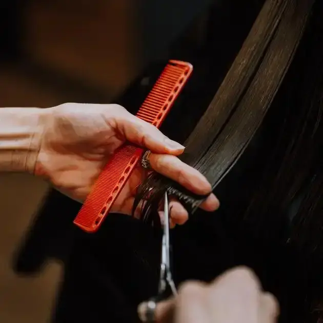 Foto som viser hår som blir klippet med saks og kam